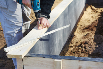 gardener screwing on wooden plank to build a raised bed - Petals & Gardens | Gardening Tips gardener screwing on wooden plank to build a raised bed